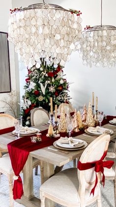 a dining room table set for christmas with red and white decorations on the table,