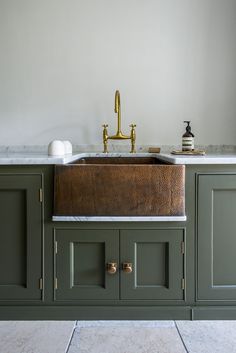 a kitchen sink sitting under a faucet next to green cabinets