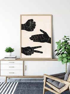 two hands pointing towards each other in black and white on a wall above a chair