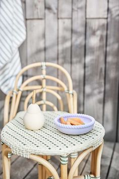 a wicker table with a bowl of food on it next to a wooden chair