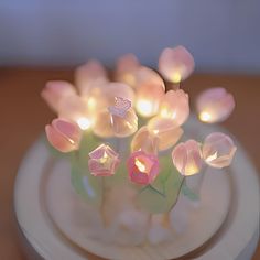 a white plate topped with pink flowers on top of a wooden table next to a candle