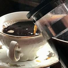 a cup of coffee sitting on top of a white saucer next to a pot