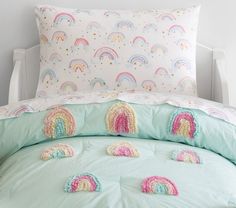 a bed with rainbows and stars on the pillowcase is in front of a white wall