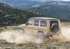 a jeep driving through the dirt in front of mountains