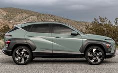 a light green suv parked in front of a mountain