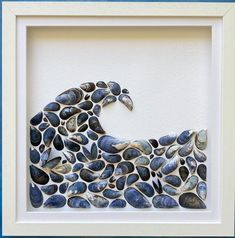 an art piece made out of seashells in a white frame