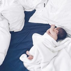 a baby wrapped in a blanket on top of a bed