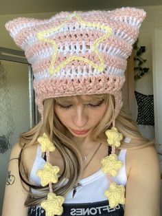 a woman wearing a pink and white crocheted hat with yellow stars on it