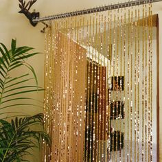 a curtain with gold sequins hanging from it's side in front of a potted plant