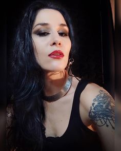 a woman with long black hair and tattoos on her arm, posing for the camera