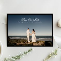 a couple holding hands while standing next to each other on top of a rock near the ocean