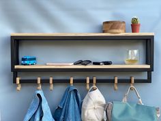 a wooden shelf with clothes hanging on it and a glass of wine next to it