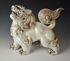 a white ceramic dog figurine sitting on top of a gray surface with its mouth open