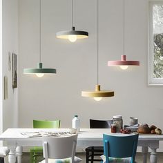 a dining room table and chairs with lights hanging from the ceiling