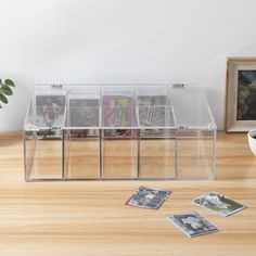 a clear plastic storage container with pictures on the floor next to a potted plant