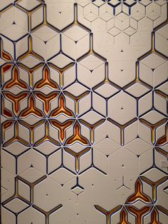 an abstract painting with hexagonal shapes and colors on the wall in front of it