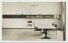 an old black and white photo of a dining room table with four chairs in it