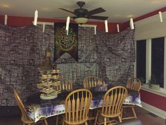 a dining room table with chairs and a fan in front of a stone wall that has hogwart's crest on it