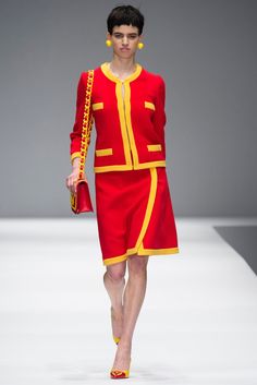 a model walks down the runway in a red and yellow outfit