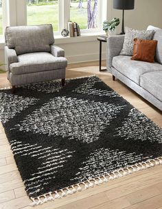 a living room area with two couches and a rug on the floor in front of a window