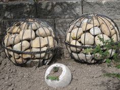 two wire baskets filled with rocks sitting on the ground next to a rock planter