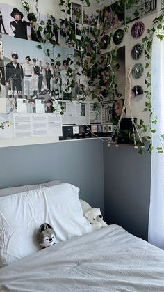 there is a bed with white sheets and plants on the wall