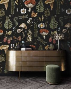 a wallpapered with flowers and plants on a black background is next to a gold sideboard