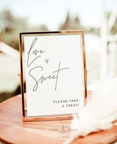 a sign that says love is sweet please take a treat on top of a wooden table