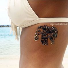 an elephant tattoo is on the side of a woman's stomach at the beach