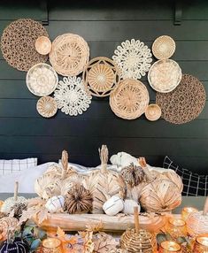 an arrangement of pumpkins and gourds are arranged on a table in front of a wall