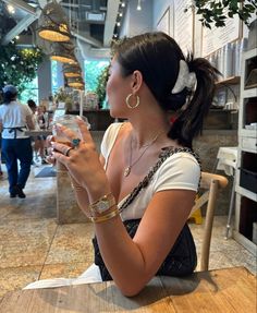 a woman sitting at a table drinking from a glass