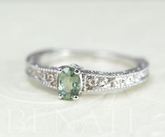 Exclusive to Benati. Green sapphire engagement ring with a antique vintage feel. Crafted to perfection in solid 14k white gold. A unique brilliant engagement ring with beautiful engraving and mill-grain details, this special engagement ring will make her blush. A brand new design inspired by the antique style I love so much. The center oval cut natural green sapphire gem is 6*4 approx. 0.50 carat. Made in the highest craftsmanship - crafted to perfection to a high polish. A unique and original e Scroll Engagement Ring, Emerald Ring Design, Green Wedding Rings, Green Engagement Rings, Antique Promise Rings, Brilliant Engagement Rings, Special Engagement Ring, Green Sapphire Engagement, Green Sapphire Engagement Ring