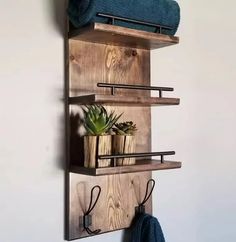 a wooden shelf with three shelves holding plants and towels