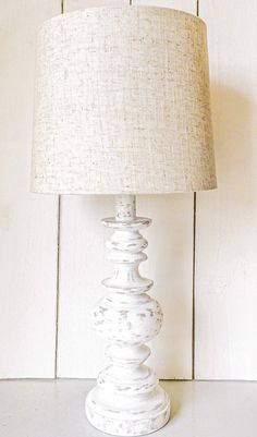 a white lamp sitting on top of a table next to a wooden wall and floor