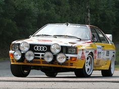 an old yellow and white race car driving down the road