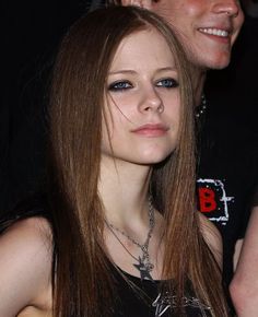 a woman with long hair standing next to a man wearing a black shirt and necklace