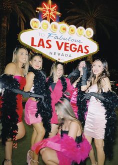 a group of women dressed in pink and black posing for a photo at the welcome to fabulous las vegas sign