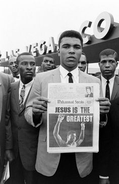 black and white photograph of men in suits holding up a sign with jesus is the greatest
