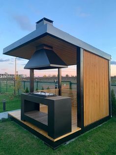 an outdoor hot tub in the middle of a grassy area with a grill on it