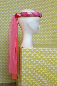 a white mannequin head with a pink scarf around it's neck on top of a box