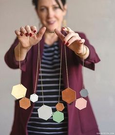 a woman is holding up her necklaces with hexagonal shapes hanging from it