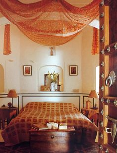 a bed sitting in a bedroom next to a window with curtains on top of it