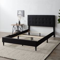 a black bed frame sitting on top of a white rug