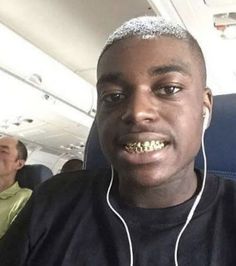 a man wearing headphones on an airplane with other people in the back ground behind him