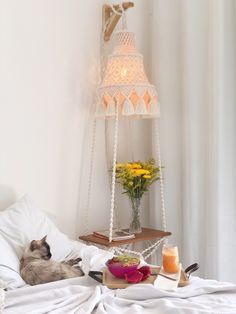 a cat laying on top of a bed next to a table with food and drinks