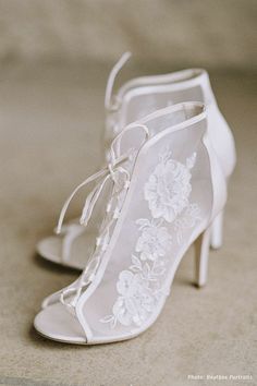 a pair of white high heeled shoes sitting on top of a floor