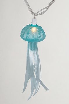 a blue light hanging from a string on a white wall in the shape of a jellyfish