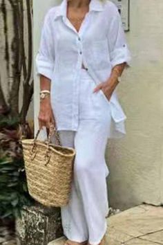 a woman in white is holding a wicker basket and posing for the camera with her hand on her hip