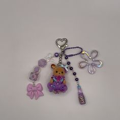 a keychain with a teddy bear and other items attached to it on a white surface