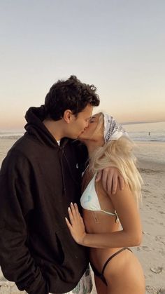 a man and woman kissing on the beach